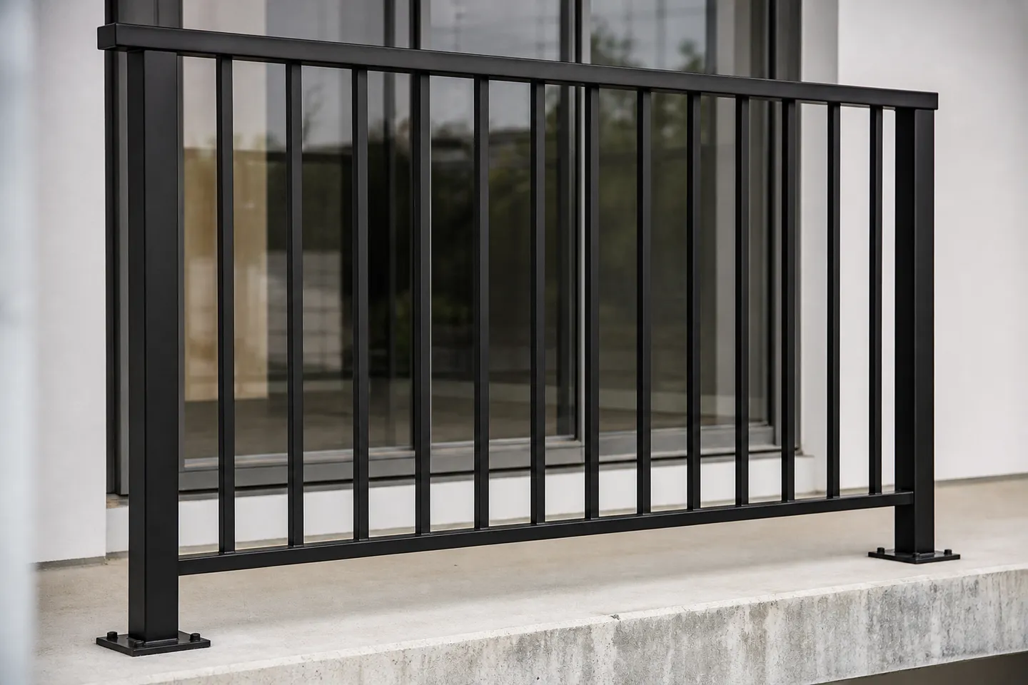 A black powder-coated aluminium balustrade with square posts, a flat top rail and evenly spaced vertical bars along the edge of a concrete balcony