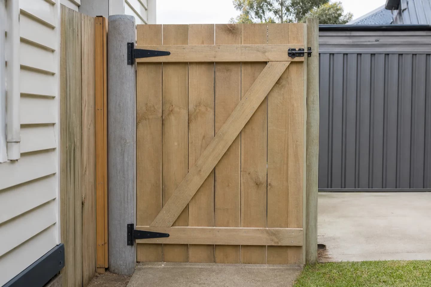 The back of a timber paling gate with two horizontal ledges and a diagonal brace rising from the bottom hinge side to the top latch side
